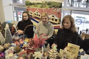 Kobiety siedzą przy stole z rękodziełami. Uśmiechają się do zdjęcia.