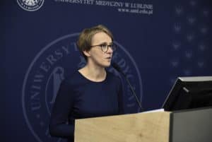 Kobieta stoi za mównicą. W tle duży baner “ Uniwersytet muzyczny w lublinie”.