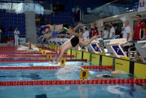 Zawodnicy rozpoczynają wyścig. Mężczyźni skaczą do wody.