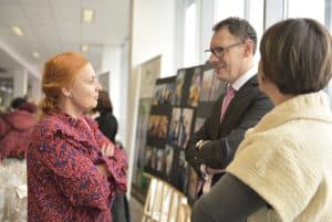 Ludzie stoją w grupie. Ich twarze są zwrócone ku sobie.