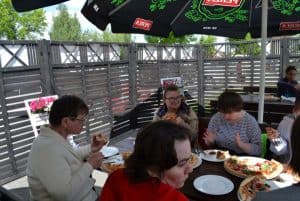 Pod parasolem cztery panie przy konsumpcji pizzy