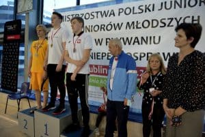 Chłopcy stoją na podium w medalach. Po prawej stronie stoją dwie kobiety i mężczyzna.