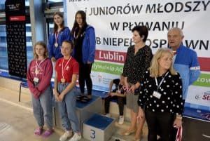 Osoby pozują do zdjęcia. To dziewczyny z medalami. Obok dwie kobety i męzczyzna.