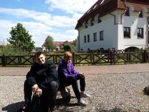 Dwóch mężczyzn na tle budynku z ogrodem patrzących w obiektyw.