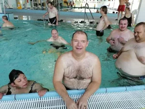 Grupa osób stoi w basenie i pozuje do zdjęcia.