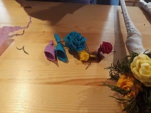 Na stole leżą kwiaty z bibuły a obok dokończona palma.