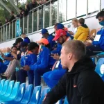 Kibice oraz zawodnicy siedzą na trybunach.