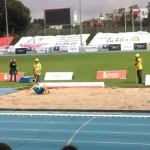 Zawodnik bierze udział skok w dal. Technicy mierzą skok.