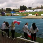 Polscy kibice kibicują zawodnikom. Kobieta trzyma Polską flagę.