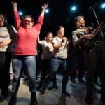 Po lewej tłum dziewczyn i kobiet tańczy, po prawej Łukasz Jemioła gra na elektrycznej gitarze