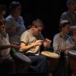 Akademia Artystyczna - grupa kobiet i mężczyzn gra na bębnach.