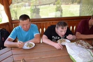 Mężczyźni jedzą posiłek siedząc w altance.