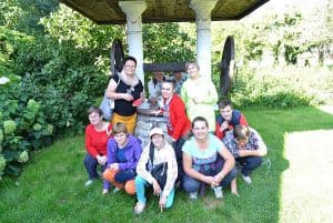 Osoby pozują do zdjęcia. Stoją przed białymi kolumnami. Wśród nich są kobiety i mężczyźni.