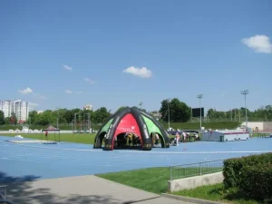 Na bieżni lekkoatletycznej stoi namiot a w nim są ludzie.