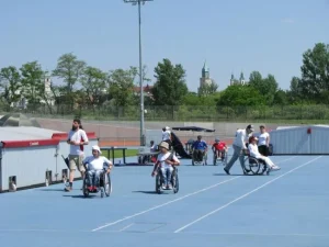 Na torze są osoby na wózkach inwalidzkich oraz osoby zdrowe.