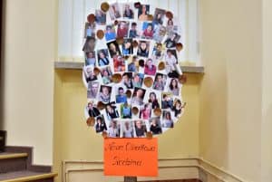 W centrum znajduje się papierowe drzewo stworzone z dwóch kawałków papieru. Pień w kolorze pomarańczowym ma na sobie napis „Nasza Ośrodkowa Rodzina”. Na koronie drzewa przyklejone są zdjęcia osób oraz naturalne suche liście.