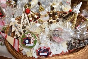 W wiklinowej tacce znajdują się ozdoby świąteczne. Są to drewniane choinki – bombki ozdobione koralikami, koronką oraz małymi szyszkami. Na dnie tacki znajdują się inne ozdoby – białe – w różnych kształtach: serca, choinki.