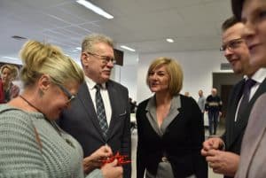 Grupa ludzi stojących w grupie. Jedna kobieta w dłoniach trzyma czerwoną gwiazdę. Inna z kolei kobieta uśmiecha się.