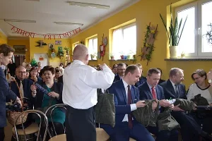 Ludzie siedzą na krzesłąch. Są ubrani wizutowo.