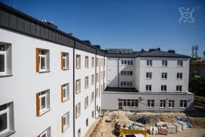 Biały budynek wielopiętrowy z ogrodem w remoncie