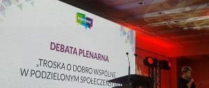 Ekran multimedialny wyświetlający - Debata plenarna, troska o dobro wspólne w podzielonym społeczeństwie.