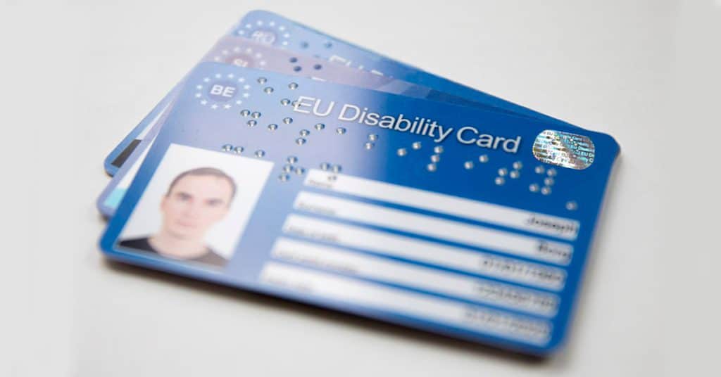 Trzy rozłożone niebieskie karty ze zdjęciem i tytułem EU Disability Card