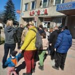 Grupa przybyszów w tym dzieci w oczekiwaniu przed budynkiem zajazdu Elf.