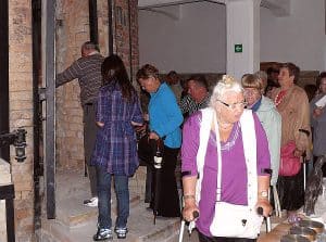 Ludzie stoją w grupie. Kobieta z mężyzna stoją na schodach. Niektorzy są o kulach