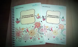na zdjęciu bruliony z napisem na środku okładki Tyfloprzewodnik po zamojskim zoo. Wokoło grafiki kwiatów i ptaków