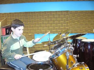 Chłopiec gra na perskusji. W tle na ścianie pianka wygłuszająca.