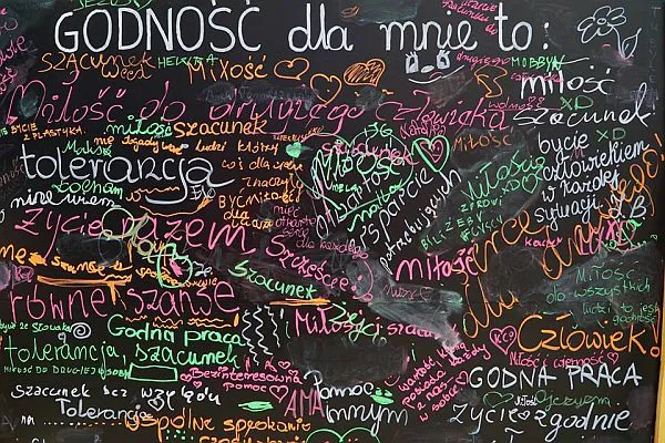 Tablica kredowa na której napisane jest “Godność dla mnie to:” i różnymi kolorami różne słowa m.in. człowiek, tolerancja, miłość.