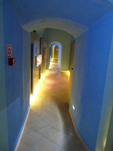 Hol. Na ścianach wiszą obrazy. Są różne witryny prowadzące do różnych pokoi.