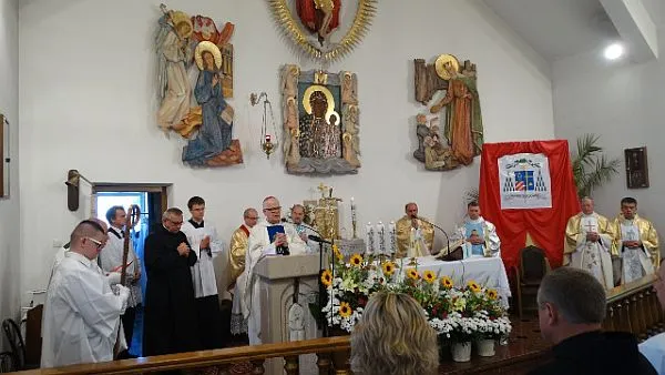 Ksiąza stoją przed ołtarzem. W tle ludzie w ławach kościelnych