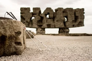 Na zdjęciu są dwie laski dla niewidomy na tle Kamiennego Monmentu Obozku koncentracyjnego Majdanek.