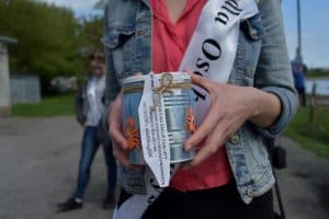 Osoba trzyma puszkę na której jest napis: “ Zbiórka na zakupy szalupy, jej remont i umożliwienie osobom z niepełnosprawnością uprawianie żeglarstwa. nr zbiórki: 2018/604/OR”.