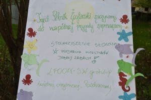 Plakat z napisem: “ Trzeci Piknik Żeglarski zaczynamy, do wspólnej przygody zapraszamy… Stowarzyszenie Słoneczko pozdrawia uczestników dobrej zabawy! LFOON-SW gratuluje świetnej organizacji. Pozdrawiamy!” Wokół napisu naklejki stworzeń morskich jak rozgwiazda, ryba.