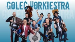plakat na którym jest band golec uorkiestra, Ludzie pozują do zdjecia z instrumentami. Uśmiechają się.