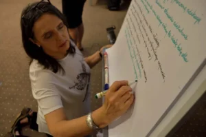 Kobeta pisze na tablicy papierowej. Uśmiecha się.