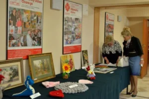 Kobiety pochylają sie nad stołem z rękodziełami.