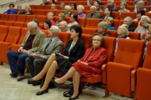 Ludzie siedzą na widowni. Uśmiechają się