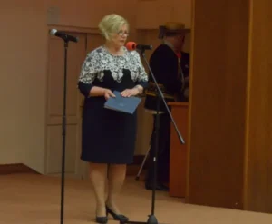 Kobieta stoi na scenie. Obok niej mikrofon.