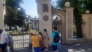 Uczestnicy stoją przed bramą wpatrzeni w pomnik Jana Pawła II.