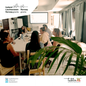 Kilka młodych osób siedzących przy stole, rozmawiających