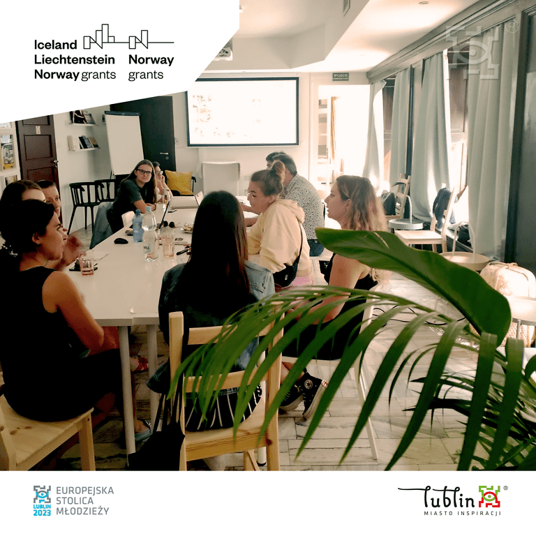 Kilka młodych osób siedzących przy stole, rozmawiających