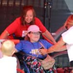 Osoba pełnosprawna z użytkowniczką na wózku inwalidzkim, podczas zabawy na huśtawce integracyjnej firmy TermaMed