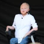 Mówca motywacyjny Łukasz Krasoń, na wózku elektrycznym i kaniulą donosową podczas swojego wystąpienia