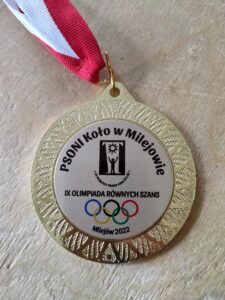 bliżenie na złoty medal z grawerem: PSONI Koło w Milejowie. Poniżej logo PSONI z hasłem Otwórzmy przed nimi życie. Pod logiem napis: IX OLIMPIADA RÓWNYCH SZANS. Poniżej flaga olimpijska i tekst: Milejów 2022.