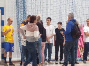 Grupa osób stojąca na sali gimnastycznej.