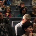 Dużo osób obydwu płci siedzących na widowni