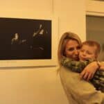 Pani Natalia Dudek trzymająca na ręku dziecko, stojąca obok wyróżnionej fotografii własnego autorstwa